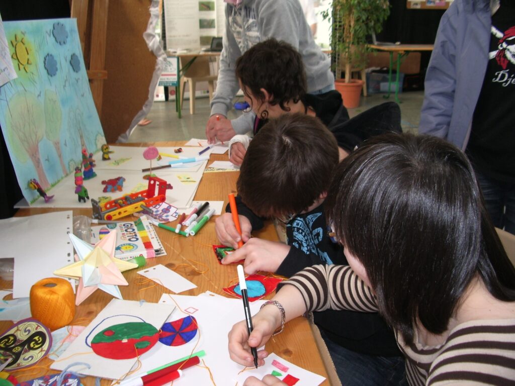 Enfants qui réalisent des dessins avec des feutres sur des feuilles. 